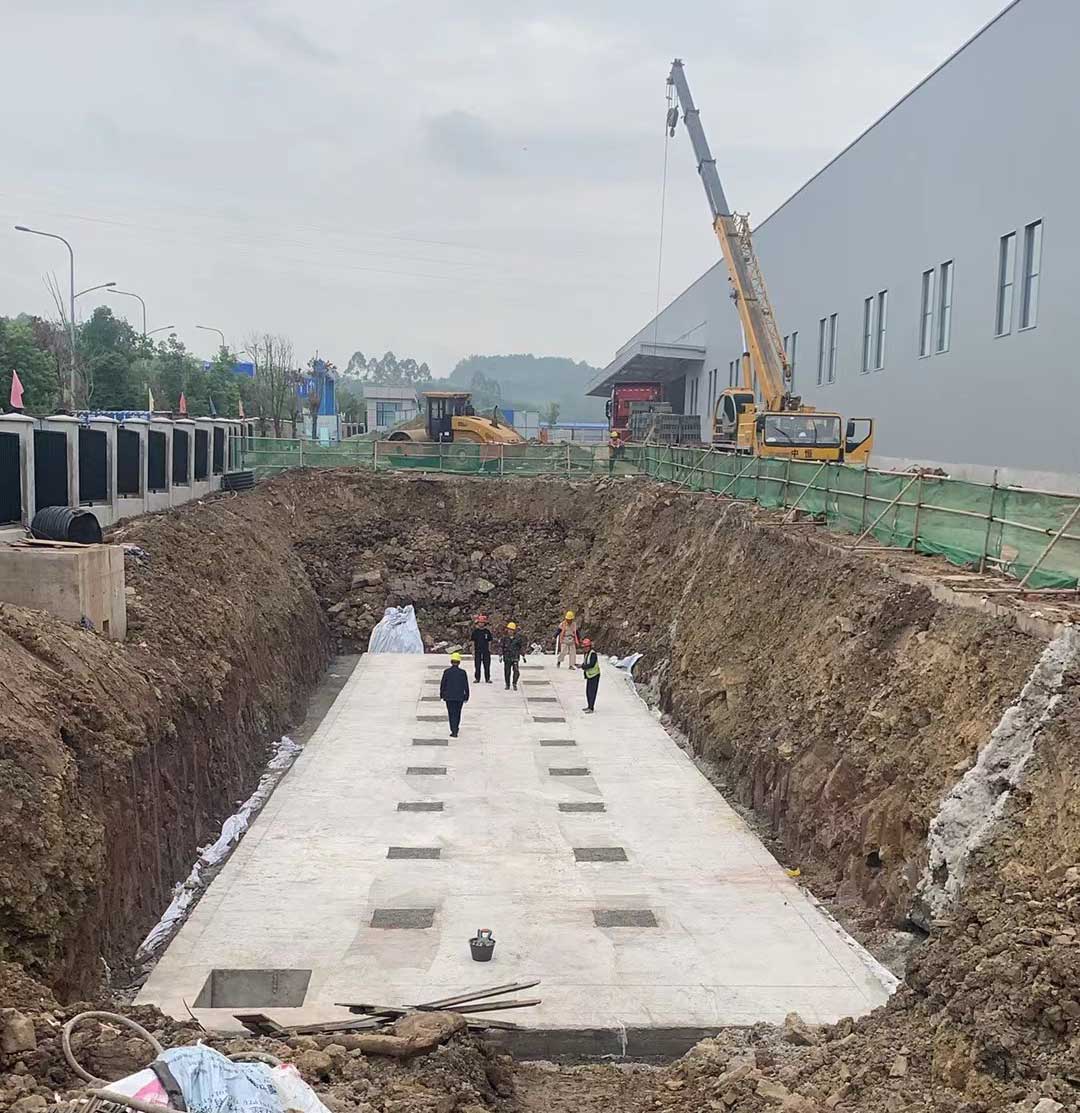 硅砂雨水收集池施工现场，基坑底部混凝土垫层浇筑完成，工人正在准备吊装作业