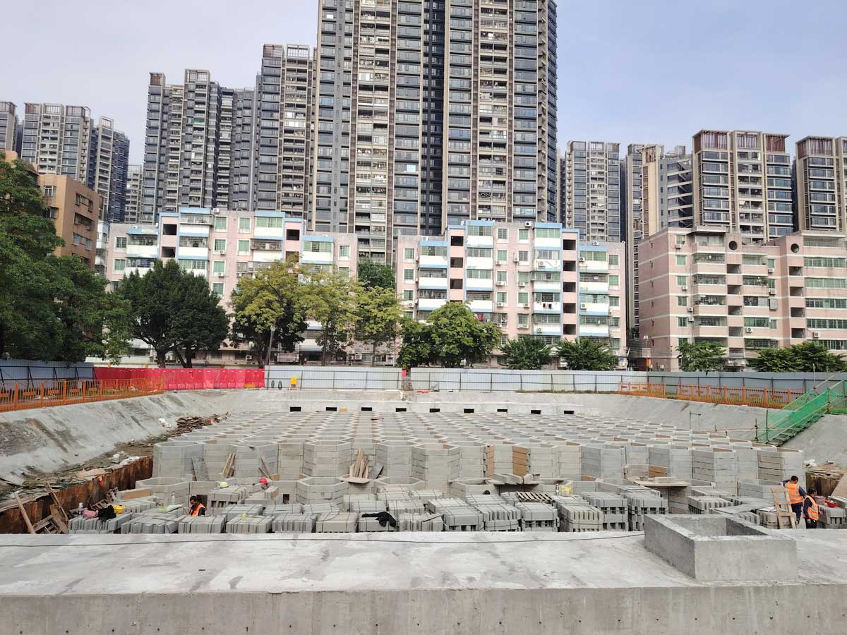 组装即将完成的地下硅砂模块雨水收集池正面全景，背景为密集的城市高楼