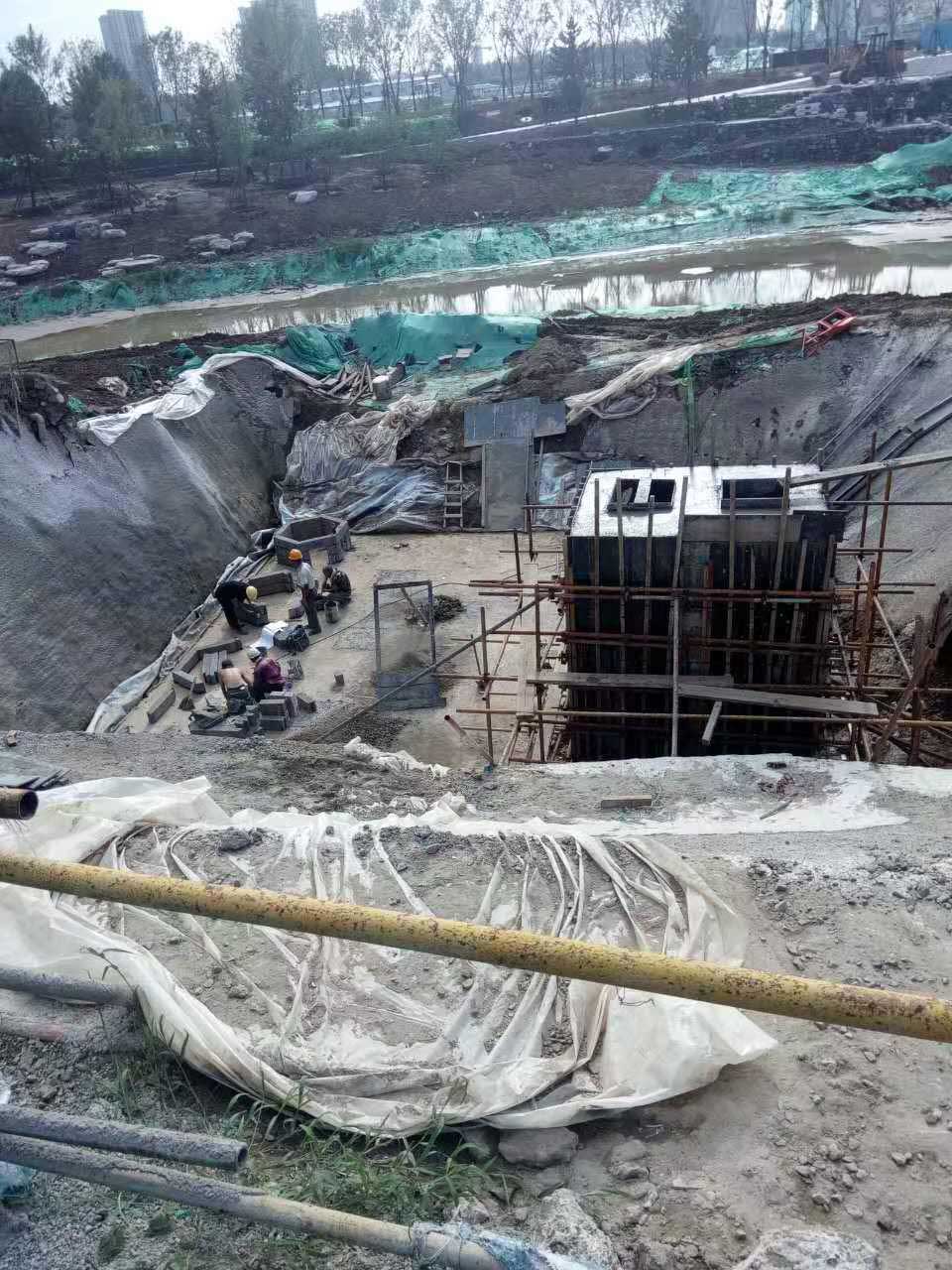 工人们正在进行地下现浇混凝土箱体脚手架搭设以及硅砂蜂巢雨水蓄水池初期底座铺设的协同施工