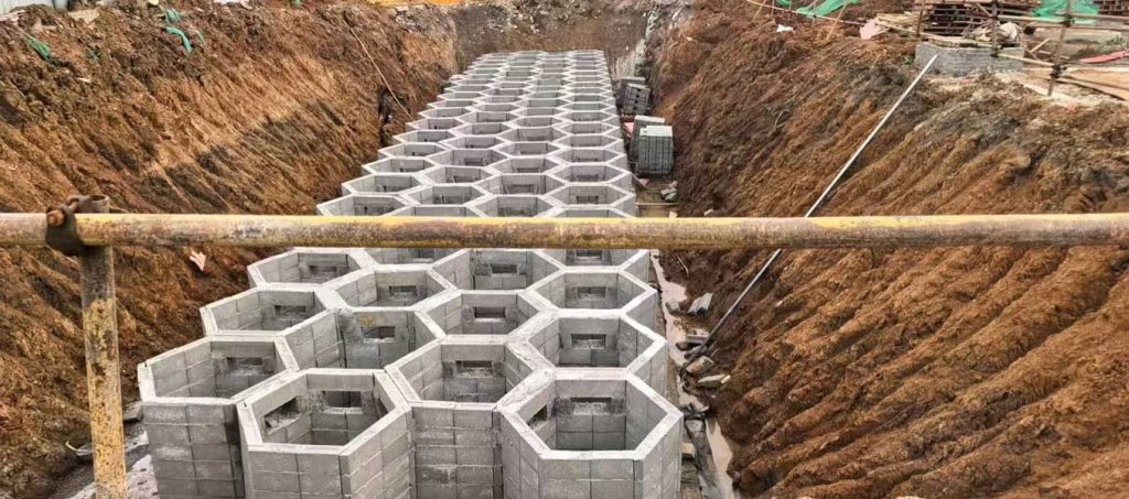 建筑工地基坑内组装结束的地下雨水收集池,整体由灰色硅砂砌块垒筑成宏观的正六边形蜂巢矩阵