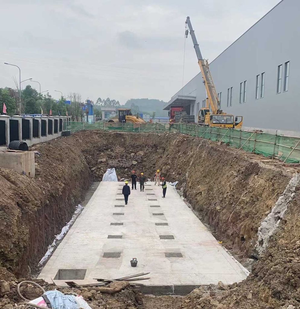 硅砂雨水收集池施工现场,基坑底部混凝土垫层浇筑完成,工人正在准备吊装作业