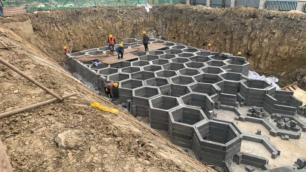 地下硅砂雨水收集池施工现场，多名工人正在基坑内拼装六边形蜂窝状蓄水模块