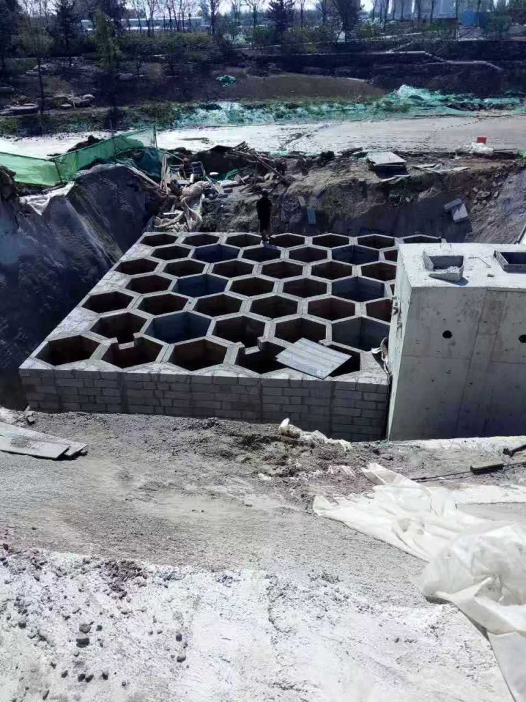 大型地下硅砂雨水收集池,展现大面积壮观且规整的六边形蜂巢网格构造与相邻的混凝土泵房