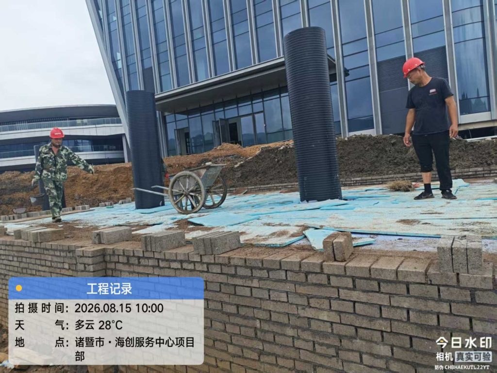 项目施工现场,工人在基坑上进行PP模块雨水收集系统检查井安装与顶部防护作业