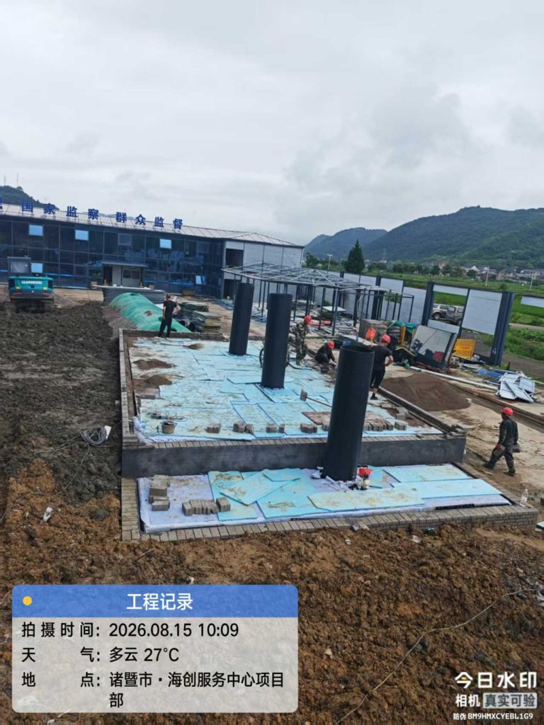 PP模块雨水收集系统施工基坑,基坑已整体铺设蓝色保温板,竖有三根黑色波纹管检查井,几名工人在上面作业