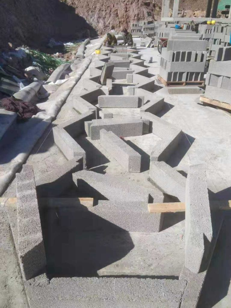 正在进行最底层模块化定位拼装的地下硅砂雨水收集池,地面上由长条砌块拼出规则的六边形蜂巢结构