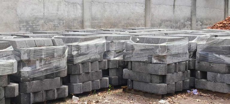户外建材仓储堆场里,成排整齐码放在木托盘上的深灰色硅砂雨水收集池模块